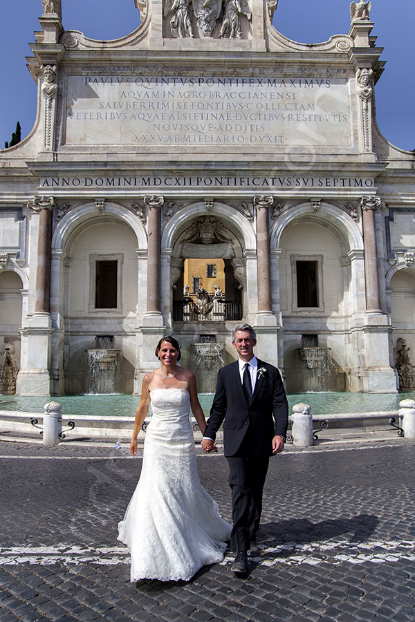 MArried couple walking in front of the Gianicolo water fountain 