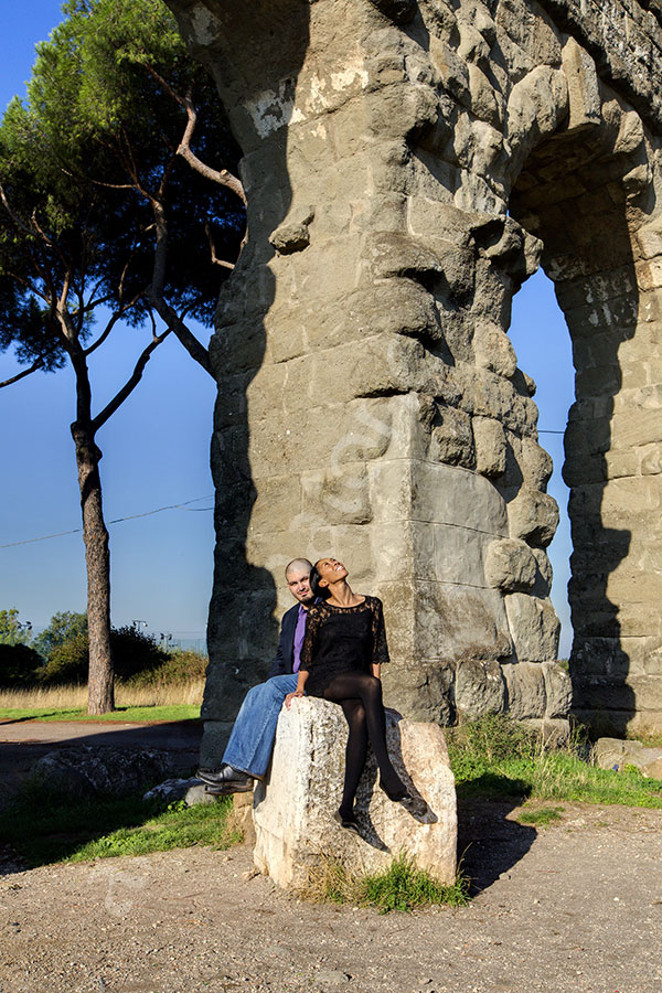 surprise-proposal-21012-028 Engaged looking up at the plane below an old ancient aqueduct in a park