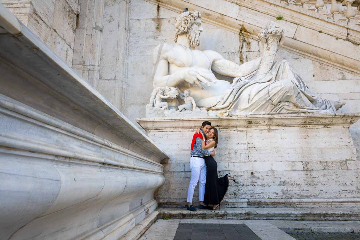 Couple portrait image taken underneath ancient white marble roman statue