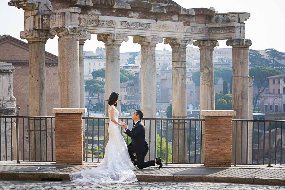 Knee down elopement marriage proposal roman forum with ancient temples and ruins background 