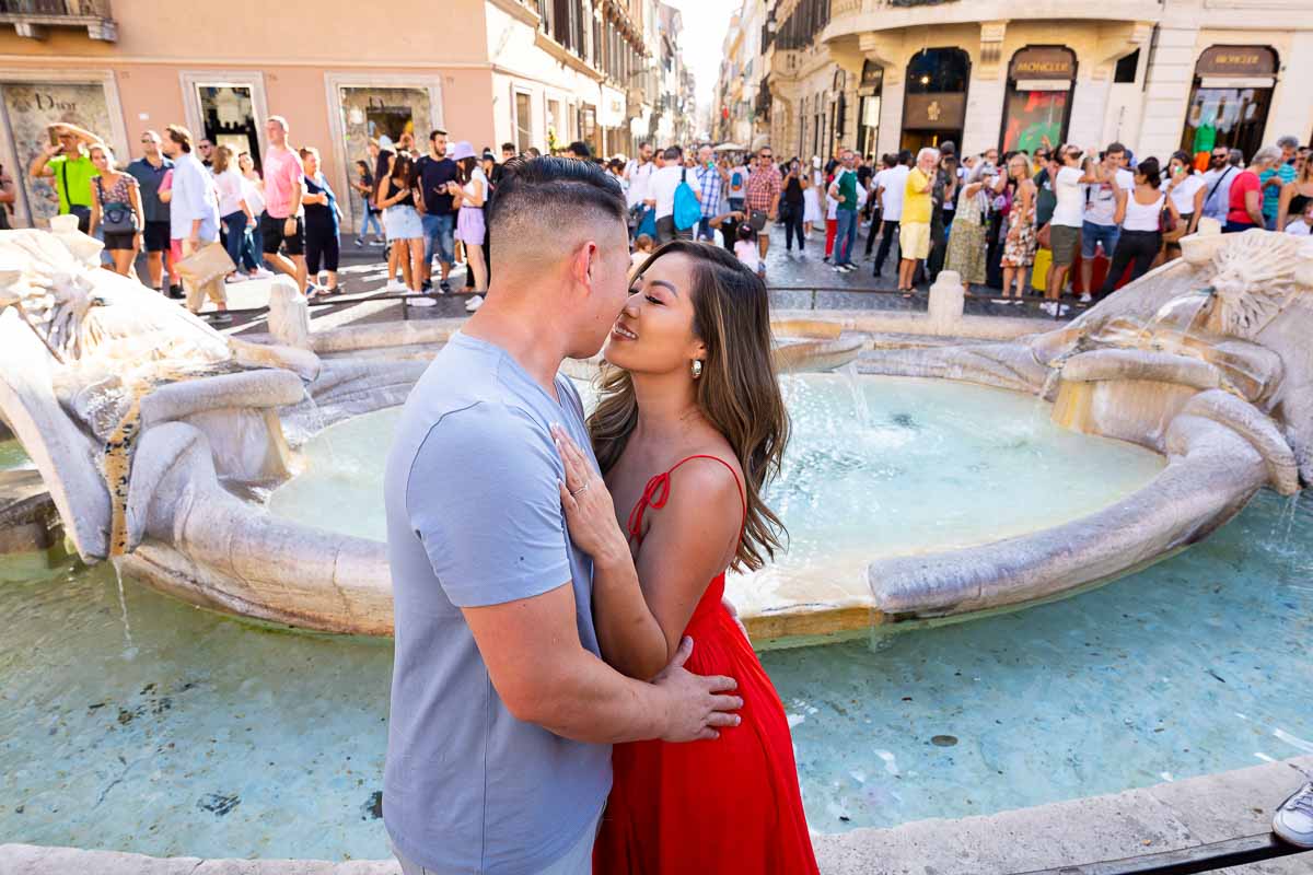 Couple kissing by the barcaccia water fountain found at the bottom of Piazza di Spagna
