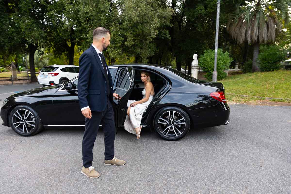 Bridal car entering the vehicle while groom is holding the door