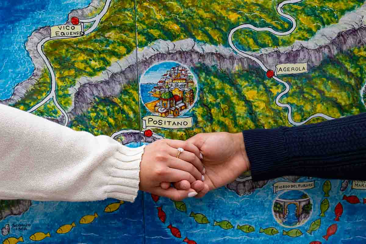 Engagement ring photos taken in front of a ceramic map town Italy right after a romantic promised