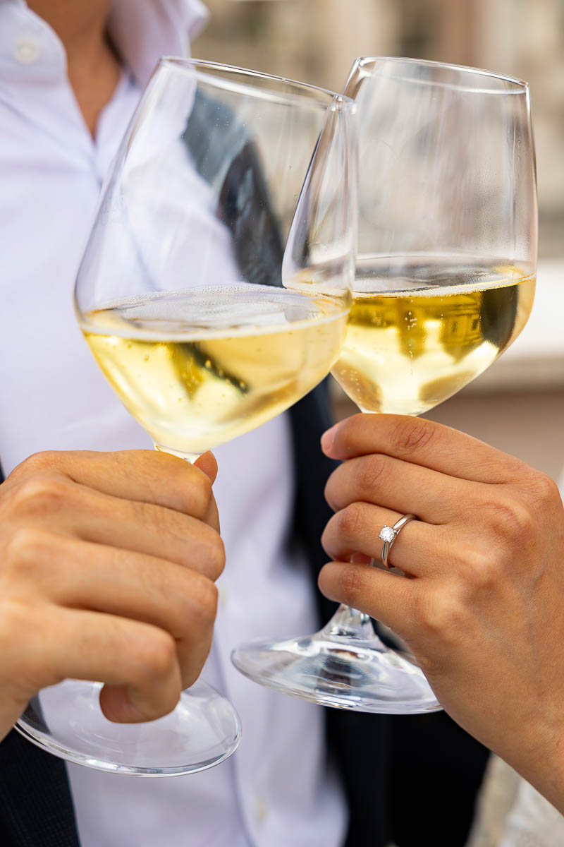 Toasting with bright yellow prosecco wine in glass flutes with the engagement ring framed in the picture