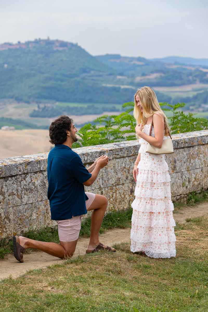 Countryside proposal in Tuscany Italy. kneeling down to ask the big question in front a scenic view of the Tuscan wolling hills