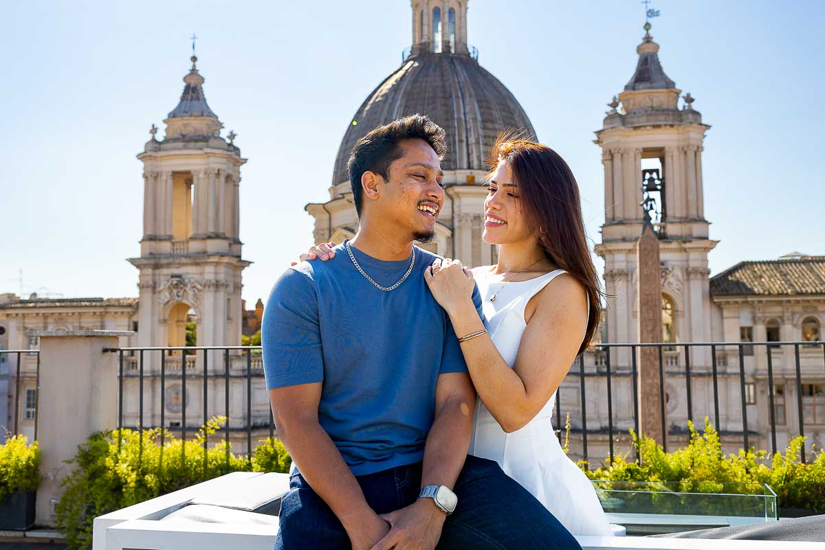Couple portrait picture sitting on a roof garden terrace with a stunning view of the city from above
