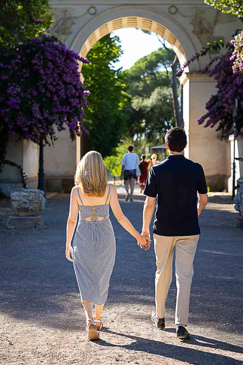 Walking holding hands towards the entrance of the Villa Borghese park. Rome, Italy