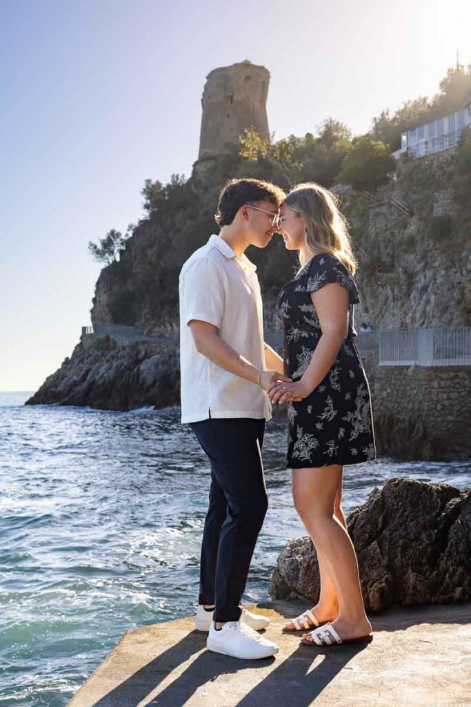 Standing together by the sea during an engagement pgotoshoot next to the water with the saracen tower in the back