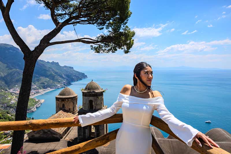 Bride with open arms photographed professionally by a photographer taking pictures over the waterscape below 