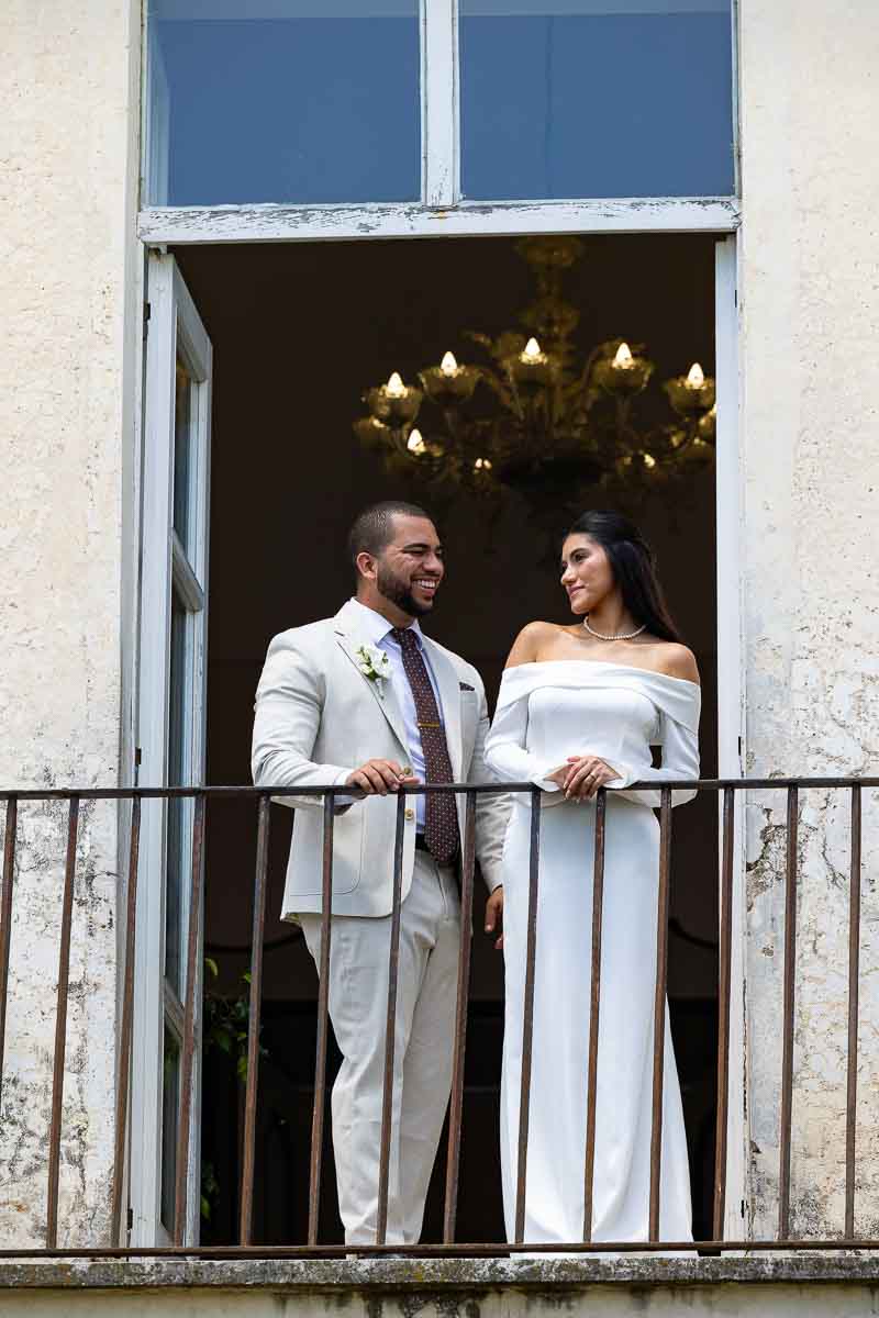 Newlywed image taken while posing on a balcony looking at each other 