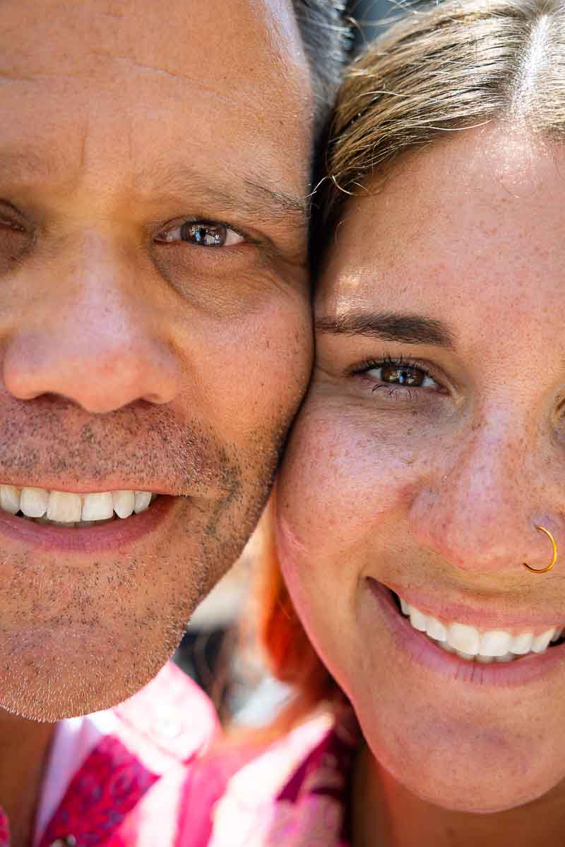 Close-up portrait photograph of two faces positioned side by side, cheek to cheek, creating an intimate split-frame composition during an engagement photo session