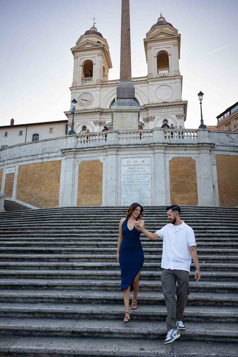 Engaged couple walking hand in hand down the Spanish Steps, capturing a graceful gesture of chivalry through natural lifestyle photography against one of Rome's most iconic staircases.