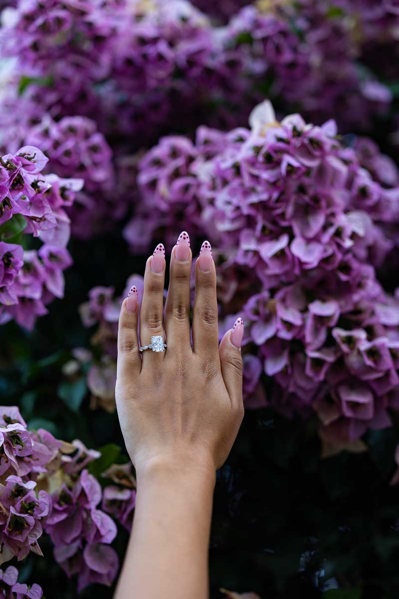 Detailed close-up of the engagement ring photographed against vibrant fuchsia bougainvillea blossoms, using a delicate still life composition with natural colours and artistic focus.
