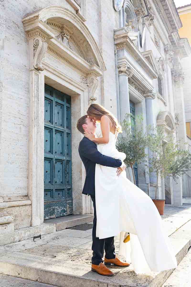 Elegant newlywed portrait on the steps of a white marble church, highlighting the ornate façade, classical details and architectural setting