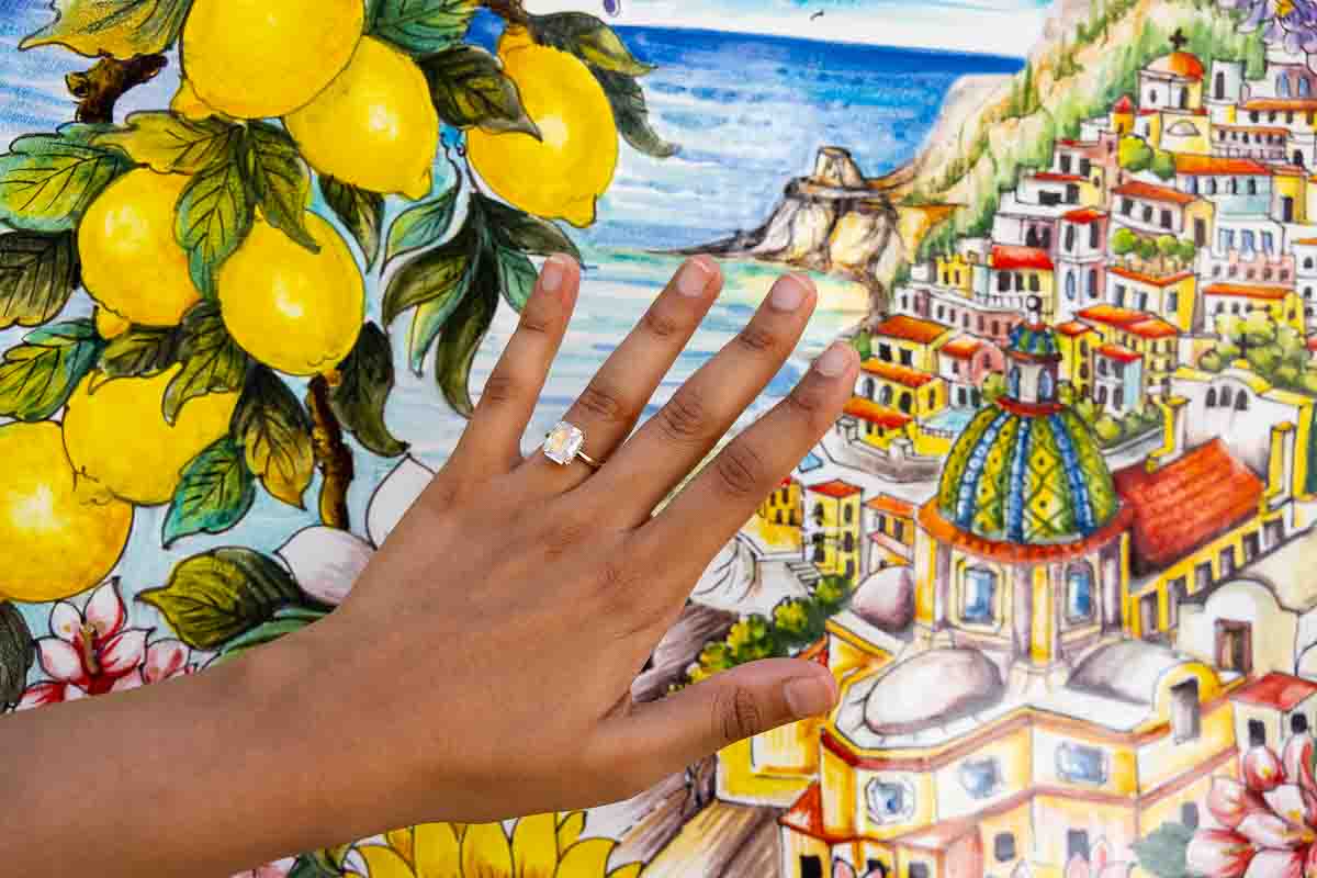 Close-up image of an engagement ring displayed over vibrant ceramic tiles painted with local lemons.